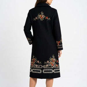 Woman wearing a black coat with floral embroidery, back view